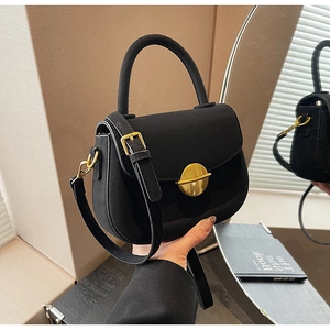 Detail of a vintage black matte crossbody bag with a round gold metal lock and handle