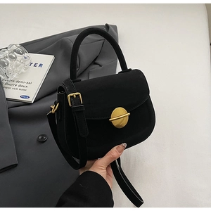 Detail of black suede handbag with round flap and decorative gold metallic disc closure