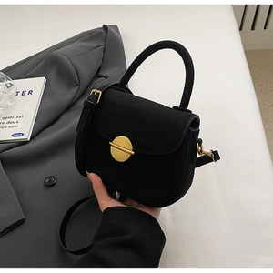 Detail of a vintage black matte crossbody bag featuring a golden circular metal buckle