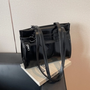 Sac fourre-tout en cuir verni noir brillant avec fermeture éclair sur un livre de bureau