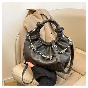 Close-up of pleated dark grey cloud bag with decorative silver ring and black bead chain