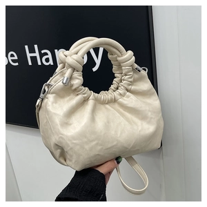 Detail view of the pleated beige cloud bag showing soft leather texture and knotted handle