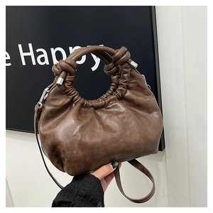 Close-up of the dark brown ruched cloud bag featuring a knotted handle and silver metal accents