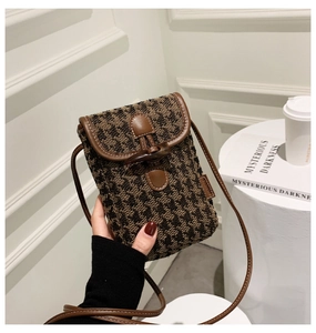Detail of checkered houndstooth phone bag with leather trim and horn buckle closure