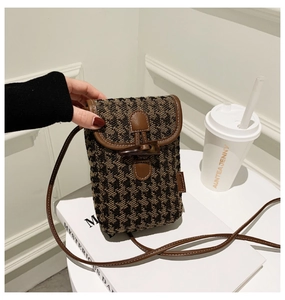 Close-up of checkered crossbody phone bag with brown leather trim and horn buckle closure