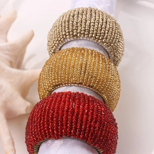 Macro shot of handcrafted beaded napkin rings in gold and burgundy with micro beads