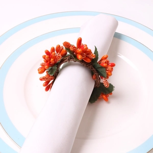 DIY Christmas napkin ring with orange berries and green leaves on a white ceramic plate