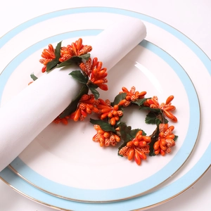 Christmas napkin ring set with orange berries and green leaves on white plates