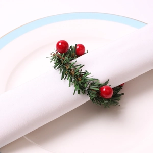 Detail of Christmas napkin ring featuring faux pine needles and bright red berries on a plate