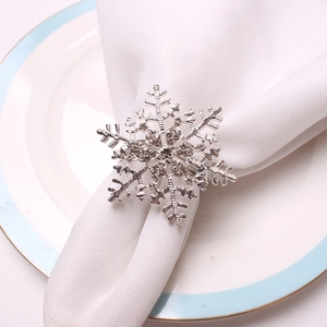 Macro shot of silver snowflake napkin ring with rhinestones on a white fabric napkin