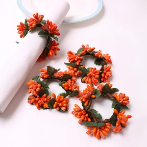DIY Christmas napkin rings featuring orange berries and green leaves on vine base