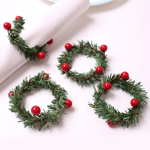 Close-up of berry wreath napkin rings with green pine needles and red festive berries