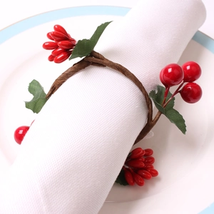 Christmas napkin ring with red berries and green leaves on white linen napkin
