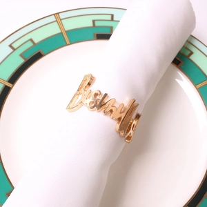 Servilletero dorado con letra Bismillah sobre servilleta blanca y plato decorativo