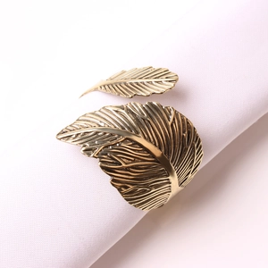 Servilletero vintage de metal dorado con forma de hoja sobre tela blanca