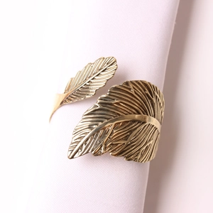 Elegante servilletero de metal dorado con forma de hoja sobre una servilleta blanca