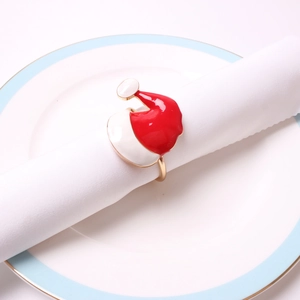 Detail view of a festive red and white enamel Santa hat napkin ring on a white plate
