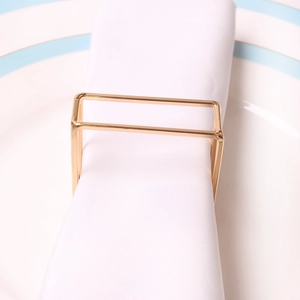 Modern gold rectangular napkin ring with metallic finish on white cloth napkin