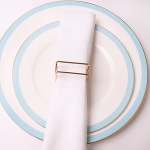 Minimalist gold rectangular metal napkin ring with geometric frame on white linen