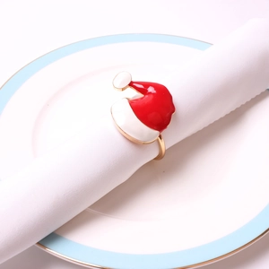 Christmas hat napkin ring in red and white enamel on a white napkin over a ceramic plate
