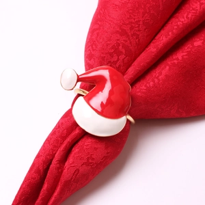 Detail of Christmas hat napkin ring with red enamel and gold finish on red napkin