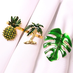Macro view of tropical napkin rings with pineapple, coconut tree and monstera leaf details
