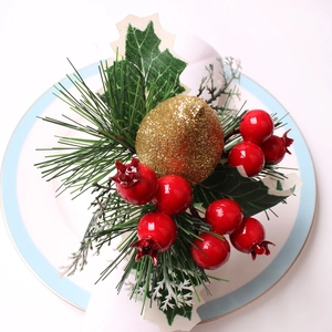 Servilletero navideño con bayas rojas y fruta dorada sobre un plato de cerámica