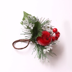 Detalle de servilletero navideño con manzana roja, agujas de pino nevadas y bayas rojas