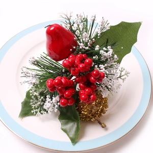 Detalle de servilletero navideño con pera roja, agujas de pino y piña dorada decorativa