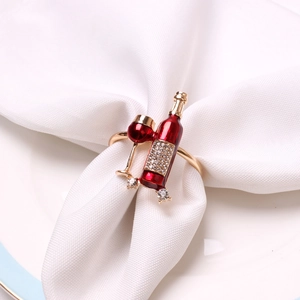 Detailed view of red wine bottle and glass napkin ring with crystals on white linens