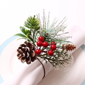 Christmas napkin ring with pine cones and red berries on a white cloth napkin
