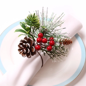 Christmas pine cone napkin ring with red berries and snow effect on white fabric
