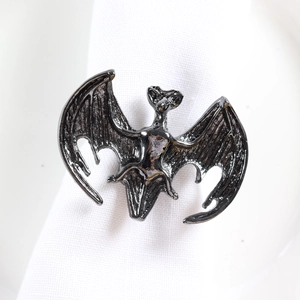Détail du rond de serviette chauve-souris noir avec textures d'ailes sur tissu blanc