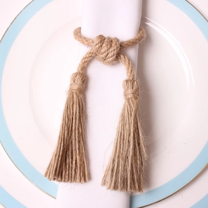 Handmade hemp rope napkin ring with double tassels on a white ceramic plate