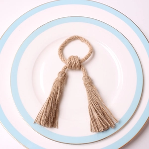 Detailed macro view of handmade natural jute rope napkin ring with rustic twin tassels