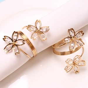 Macro shot of gold cherry blossom napkin rings with crystals on white fabric
