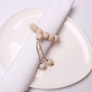 Detail of wooden bead napkin ring with jute rope tassels on a white ceramic plate