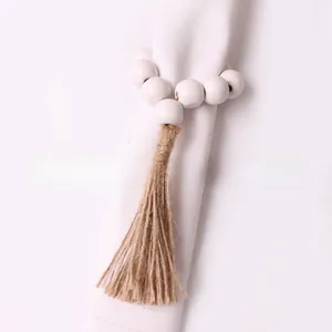 Detail of white wooden bead napkin ring with natural jute tassel for Christmas tables