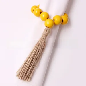 Detail of yellow wooden bead napkin ring with natural jute rope tassel on a white napkin