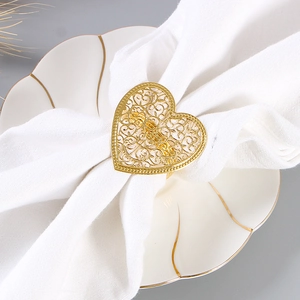 Rond de serviette doré élégant en forme de cœur avec bords perlés sur tissu blanc