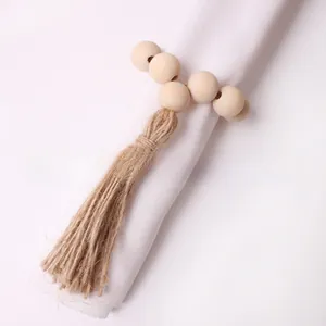 Close-up of a natural wood bead napkin ring with a rustic jute tassel on a white linen napkin