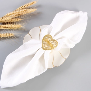 Rond de serviette coeur évidé doré avec motif filigrane sur tissu de table blanc