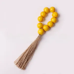 Close-up of bohemian napkin ring with bright yellow wooden beads and natural hemp tassel