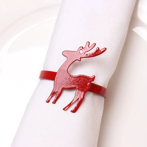 Detail of a festive red metal reindeer napkin ring on a white cloth for Christmas decor