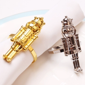 Detailed close-up of gold and silver plated nutcracker soldier napkin rings on a white cloth