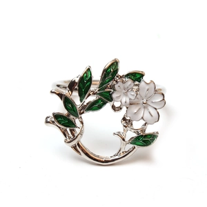 Detailed view of silver gardenia napkin ring with white flowers and green enamel leaves