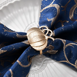 Golden pumpkin napkin ring on deep blue cloth and white plate for autumn table decor