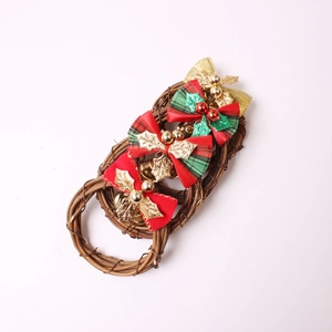 Three Christmas rattan napkin rings with red bows, gold bells, and festive leaves