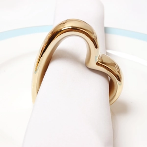 Elegant gold heart-shaped napkin ring set on a white fabric napkin and porcelain plate