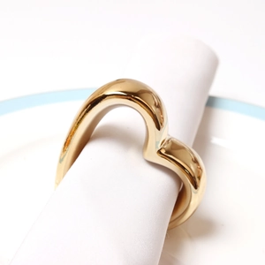 Macro shot of gold heart napkin ring on white fabric showing metallic mirror finish